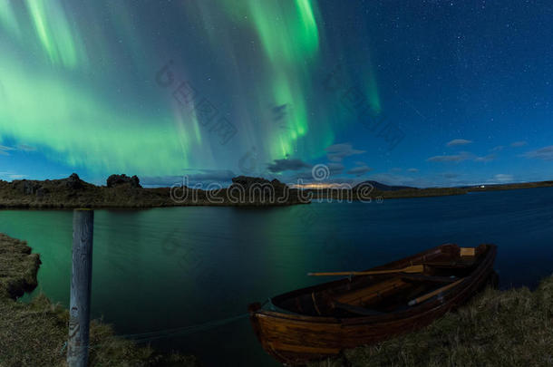 北极光在冰岛的一个湖上面有船
