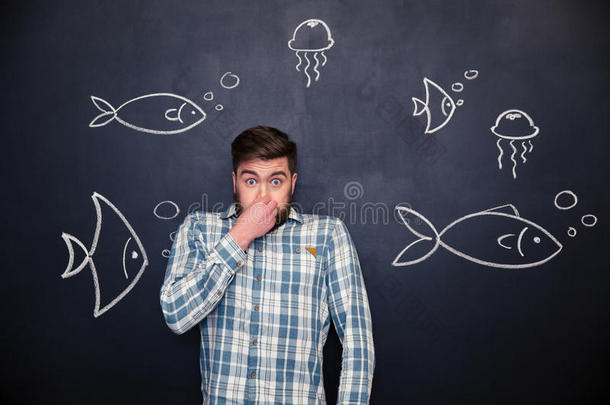 有趣的人闭上鼻子，和鱼站在黑板上