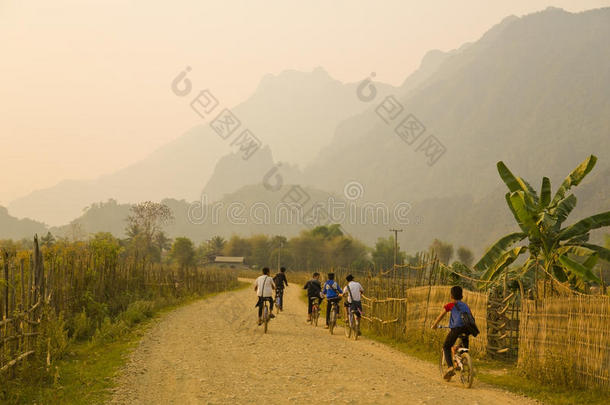 儿童骑自行车，日落在石灰石山的范维昂，老挝