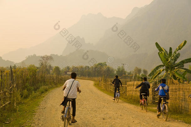儿童骑自行车，日落在石灰石山的范维昂，老挝