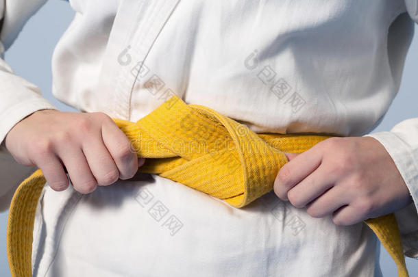 双手收紧<strong>黄带</strong>在一个穿着和服的青少年身上