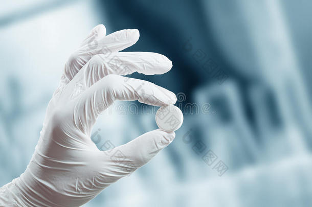 戴着医用手套的手拿着药片