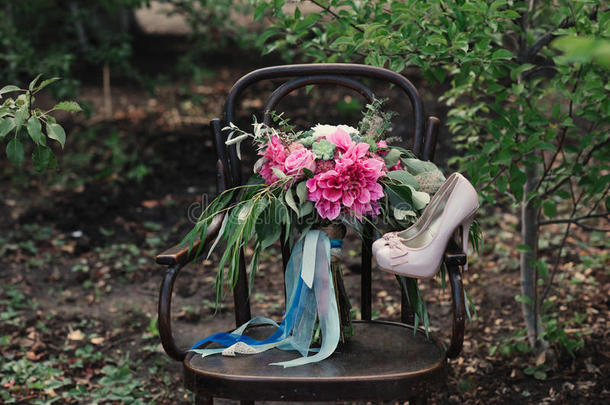 漂亮的结婚鞋，高跟鞋和一束五颜六色的花，放在大自然的老式椅子上