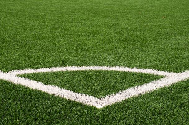 足球操场角落在人造绿色草皮地面上涂上白色线条标记。 磨碎的黑色橡胶。