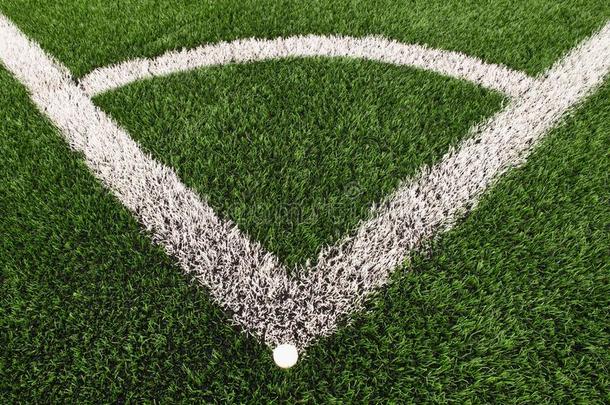 足球操场角落在人造绿色草皮地面上涂上白色线条标记。 磨碎的黑色橡胶。