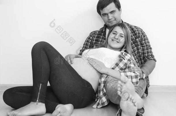 黑白照片的怀孕夫妇拥抱在地板上的客厅