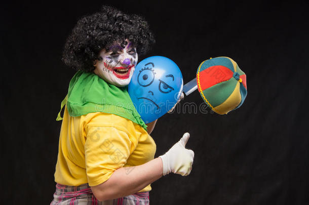 愤怒的丑陋小丑想杀死帽子里的气球