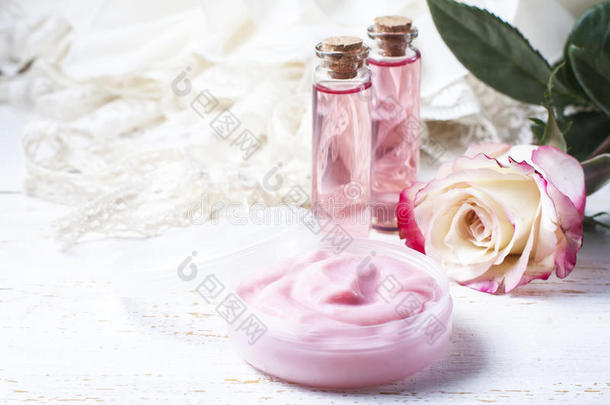木制桌子上有粉红色玫瑰的化妆品奶油