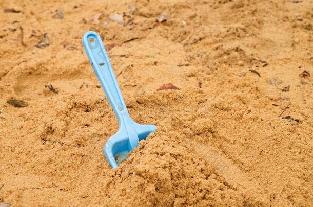 蓝色的孩子在白沙上铲玩具，玩塑料游戏。 幼儿园里的一堆沙子。