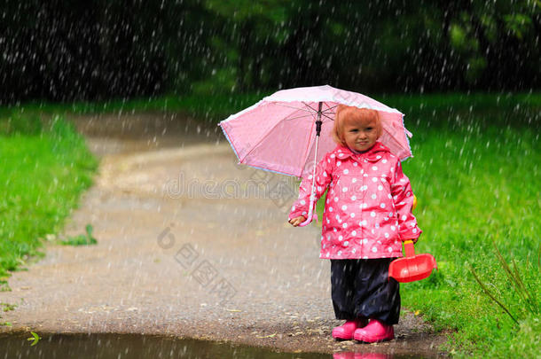 可爱的小女孩带着雨伞，穿着雨衣和靴子