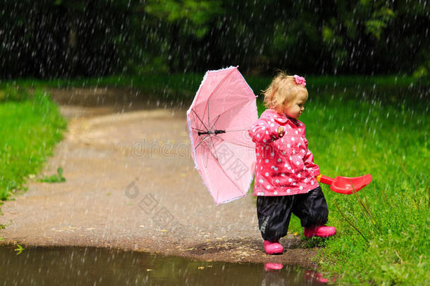 可爱的小女孩带着雨伞，穿着雨衣和靴子