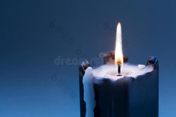黑色蜡烛，在深蓝色渐变背景上燃烧灯芯。 复制空间