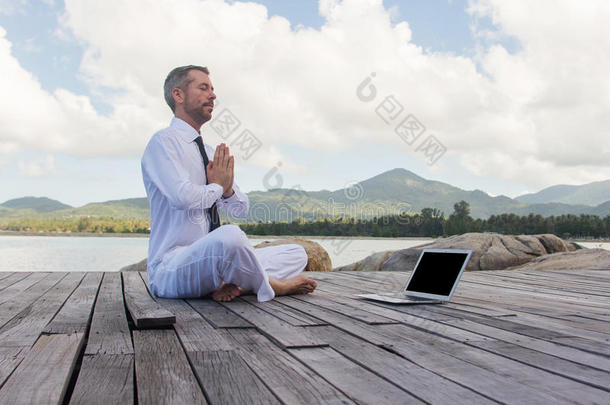 商人用笔记本电脑在木桥上做瑜伽
