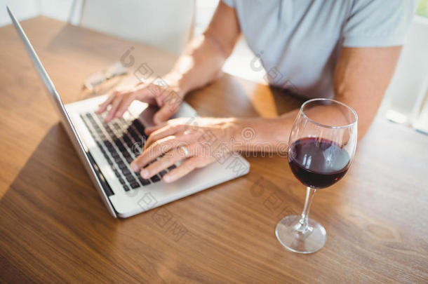 专注的老人使用笔记本电脑和喝酒