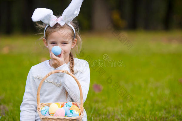 可爱的小女孩戴着兔子耳朵，在春天的户外玩复活节彩蛋