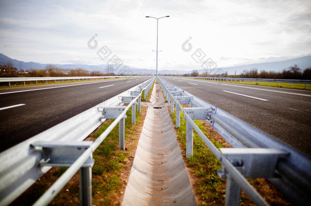 高速公路在阳光明媚的日子里，经过风景优美的绿色草地。高速公路长途行驶。沥青公路