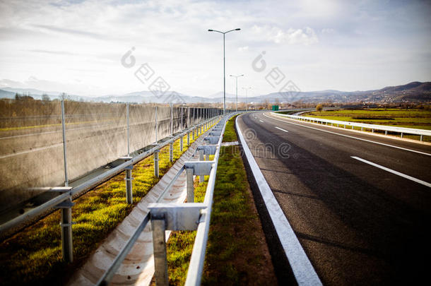 高速公路在阳光明媚的日子里，经过风景优美的绿色草地。高速公路长途行驶。沥青公路