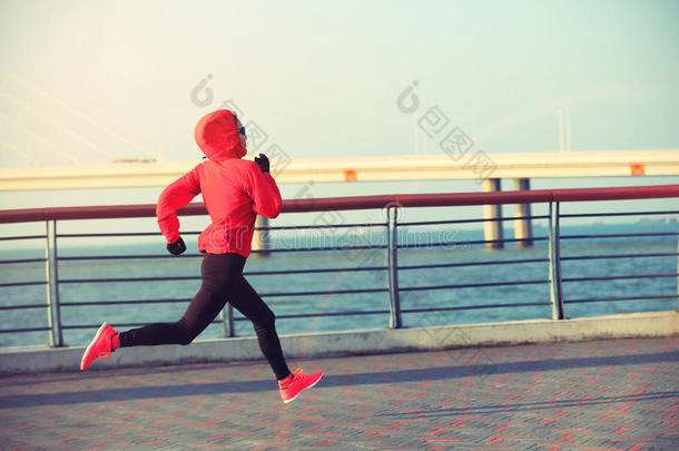 健身女跑步者在海边路上跑步