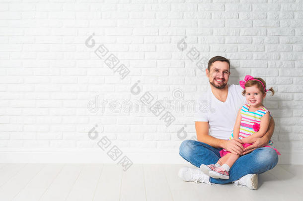 家庭父亲的孩子女儿在一堵空白的白色砖墙上