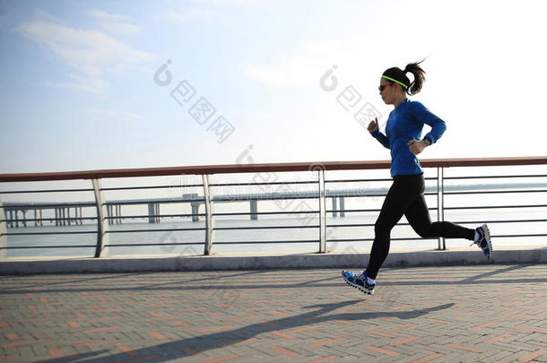 健身女跑步者在海边路上跑步
