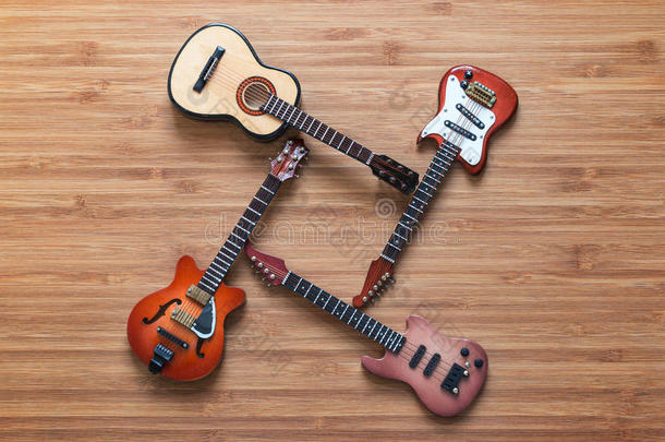 四种不同的电吉他和声学吉他在一个木制的背景。 玩具吉他。 音乐概念。