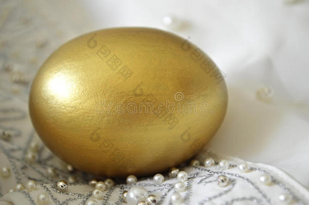 丝绸背景上的金蛋和珍珠