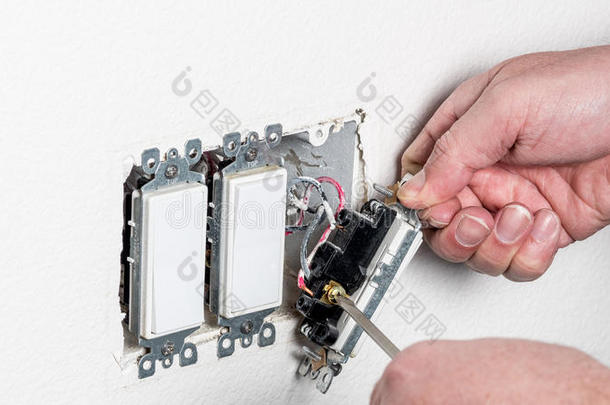 电工在白色墙上更换了一个电灯开关
