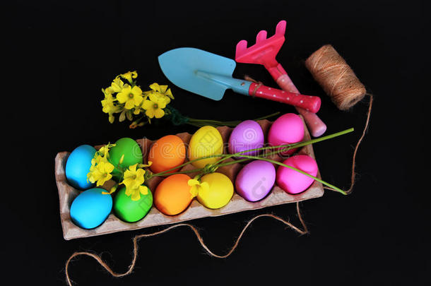 彩色复活节彩蛋与园艺工具，儿童园艺铲子，耙，绳子和春天黄花