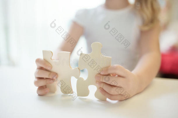抱着两个大木头拼图的女孩。 双手连接拼图。 用小Dof特写照片