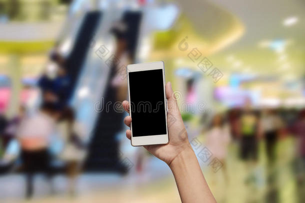 手持和触摸屏智能手机，在模糊的照片上的百货<strong>商场中</strong>心和人的背景。