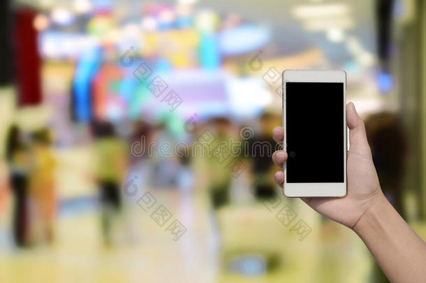 手持和触摸屏智能手机，在模糊的照片上的百货<strong>商场中</strong>心和人的背景。
