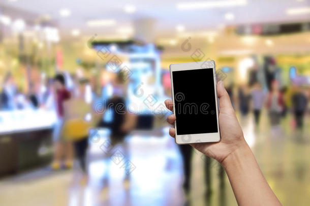 手持和<strong>触摸屏</strong>智能<strong>手机</strong>，在模糊的照片上的百货商场中心和人的背景。