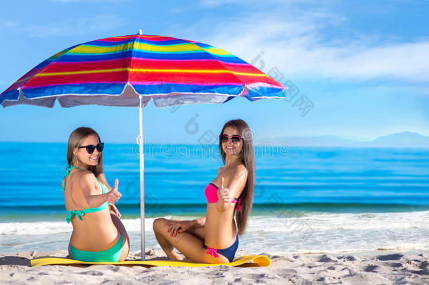 女孩子们在沙滩上打着雨伞。