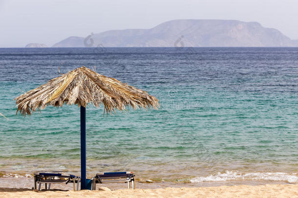 蓝色的大海，金色的沙子，沙滩上的太阳床和雨伞。 iOSI