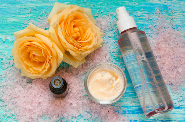 化妆品从玫瑰，奶油和一瓶玫瑰水，精油，花在绿松石木背景