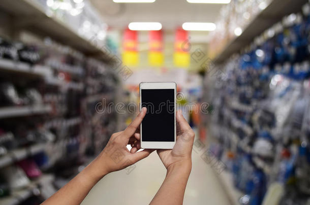 手持和触摸屏智能手机，在模糊的<strong>照片</strong>上的<strong>超市</strong>商店的背景与Bokeh。