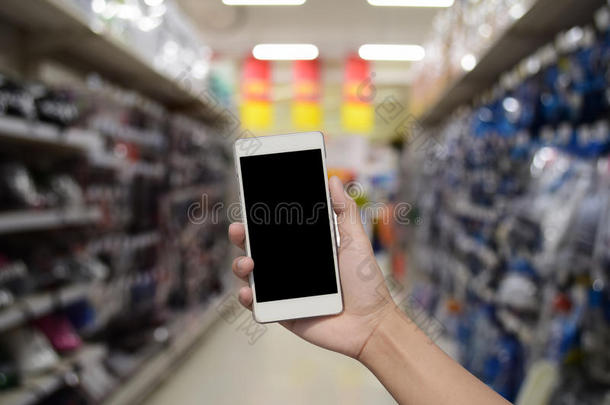 手持和触摸屏智能手机，在模糊的<strong>照片</strong>上的<strong>超市</strong>商店的背景与Bokeh。