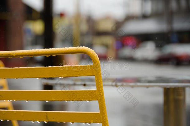 在梅瑟街的一家街头咖啡馆里，<strong>一把</strong>黄色的户外<strong>椅子</strong>的背面