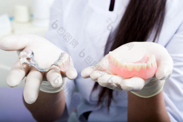 美丽的亚洲年轻女子牙医拿着假牙
