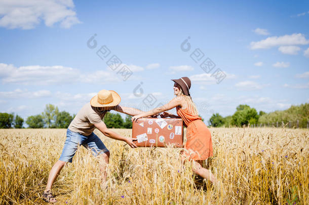 一对夫妇在野外战斗，在乡村风景蓝天背景下的手提箱户外