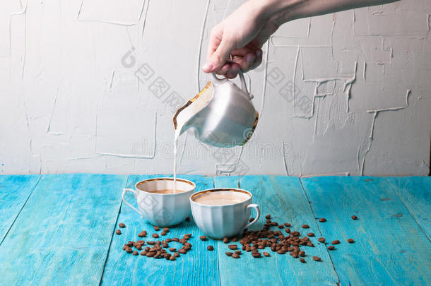 咖啡加牛奶，从送牛奶的人倒牛奶，蓝色的木制背景