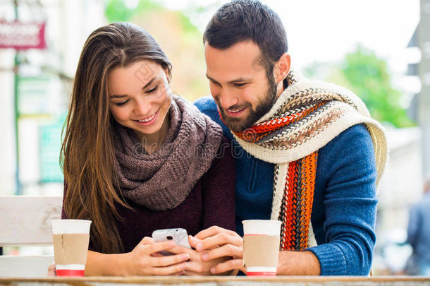在秋天的公园里，一对夫妇用手机自拍。 微笑的夫妇自拍与智能手机在城市爸爸