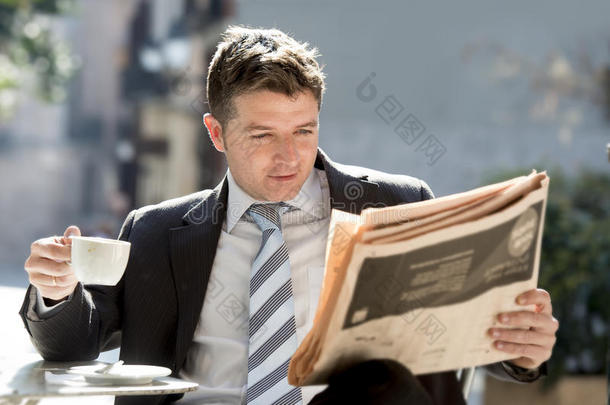 商人坐在户外吃早餐，暂停晨读新闻在报纸上喝咖啡
