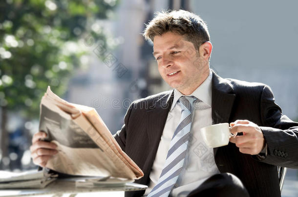 商人坐在户外吃早餐，暂停晨读新闻在报纸上喝咖啡