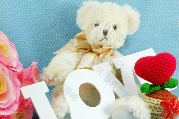 可爱的泰迪熊概念情人节蓝色波尔卡点背景和人造玫瑰花