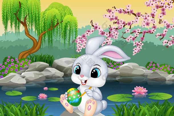 纸箱快乐复活节兔子在岩石上画一个鸡蛋
