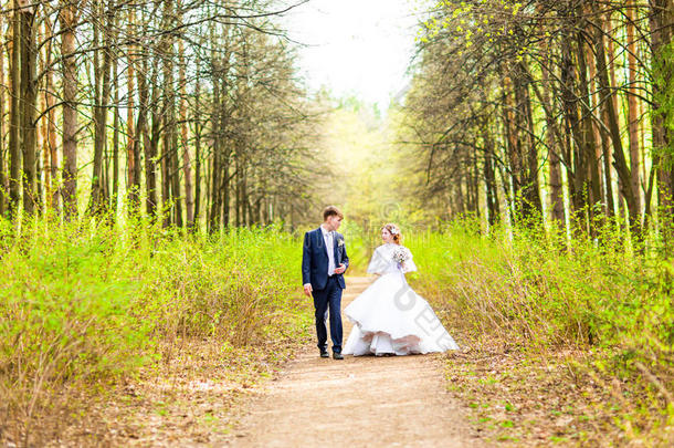 婚礼当天新娘和新郎在春天的大自然中散步。 新婚夫妇，幸福的新婚女人和男人拥抱