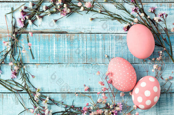 蓝色木头上五颜六色的粉红色鸡蛋和花架