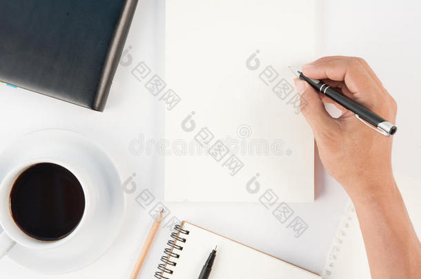 一杯热咖啡和一只手在白色的背上写笔记本