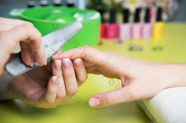 一位在美甲沙龙接受指甲锉美容师修剪指甲的妇女的特写镜头。 去修指甲的女人。 美容